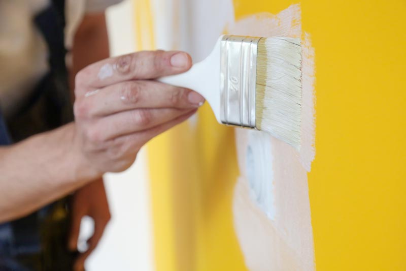 Måla med vit färg över en gul vägg
